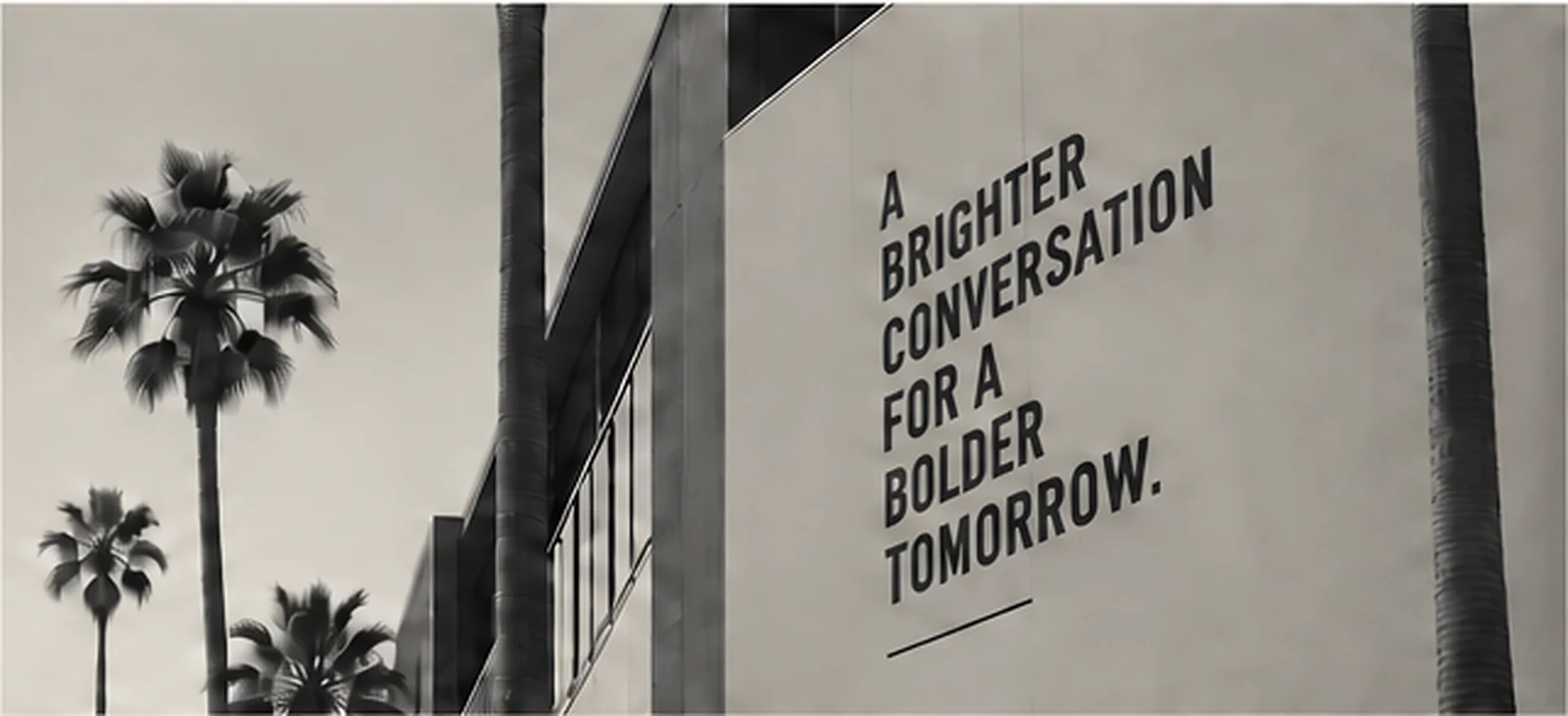 Palm trees beside a building reading A Brighter Conversation for a Bolder Tomorrow